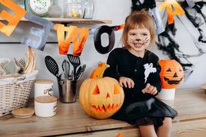 bambina seduta accanto alla zucca e mostrando un gesto spaventoso. - concetto di halloween foto