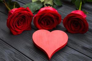 cuore rosso e rose rosse su fondo di legno scuro foto