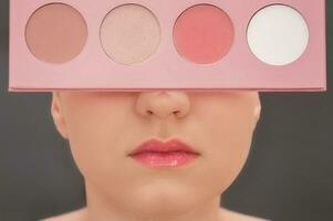 giovane bellissimo ragazza con rosa rossetto nascondiglio sua viso dietro a impostato di colorato polvere foto