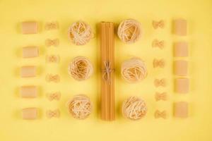 tipi assortiti di pasta su sfondo giallo. varie forme di pasta. foto