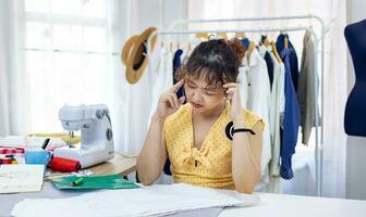 alla moda libero professionista sarta è frustrante e bruciato su progettazione il nuovo vestito utilizzando mussola mentre Lavorando nel artistico laboratorio studio per moda design e capi di abbigliamento attività commerciale industria concetto foto