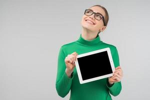 ridendo donna sognante con gli occhiali tiene il suo ipad e alza lo sguardo foto