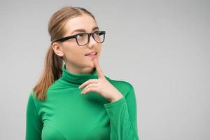 la ragazza con gli occhiali in piedi è premurosa in studio e alza lo sguardo. - Immagine foto