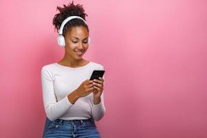 ritratto di una ragazza con gli auricolari e con in mano un telefono cellulare che guarda lo schermo - immagine foto