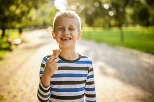 ritratto di contento ragazzo chi è in piedi nel parco e mangiare ghiaccio crema. foto