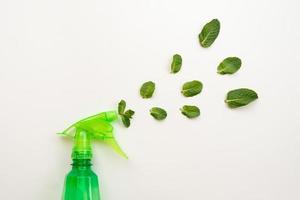 bottiglia di detersivo verde su sfondo rosa spruzzare foglie di menta fresca. - copia spazio