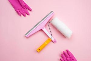 spazzola e rullo per la pulizia dei vetri per la riparazione e guanti di gomma su sfondo rosa foto