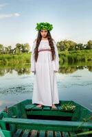 giovane donna con fiore ghirlanda su sua testa, rilassante su barca su fiume a tramonto. concetto di femmina bellezza, riposo nel il villaggio foto