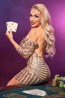 bionda donna con un' Perfetto acconciatura e luminosa trucco è in posa con giocando carte nel sua mani. casinò, poker. foto