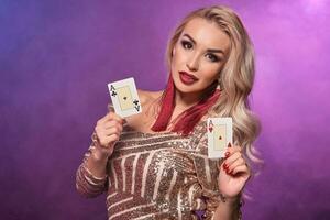 bionda donna con un' Perfetto acconciatura e luminosa trucco è in posa con giocando carte nel sua mani. casinò, poker. foto