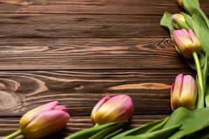 fiori di tulipani primaverili sulle tavole di legno del tavolo. biglietto di auguri per la festa della mamma, pasqua. copia spazio foto