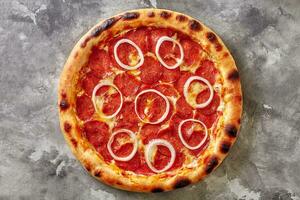 superiore Visualizza di peperoni Pizza con pomodoro salsa, Mozzarella formaggio e cipolla anelli su grigio pietra foto