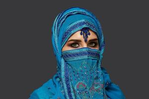 studio tiro di un' giovane bellissimo donna indossare il blu hijab decorato con paillettes e gioielleria. Arabo stile. foto