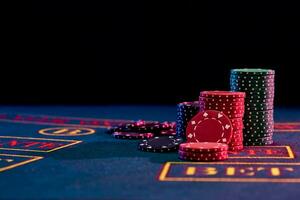 colorato patatine fritte emorroidi in piedi su blu copertina di giocando tavolo. nero sfondo. gioco d'azzardo intrattenimento, poker, casinò concetto. avvicinamento. foto