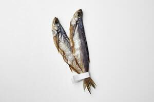 Due strattonato o secco salato pesce sciabola con carta etichette su code isolato su bianca foto