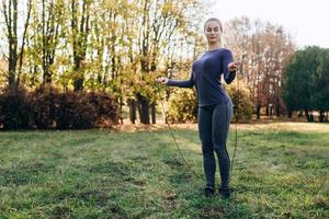 ragazza carina e snella che salta sulla corda per saltare all'aperto foto