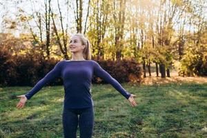 bella ragazza sorridente in palestra mattutina nel parco, guardando lontano con le braccia tese. foto