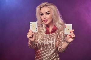 bionda donna con un' Perfetto acconciatura e luminosa trucco è in posa con giocando carte nel sua mani. casinò, poker. foto