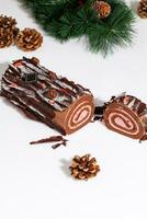 affettato cioccolato spugna torta rotolo con Natale albero ramo e dorato coni foto