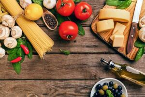 italiano cibo pomodori da cucina, basilico, pasta, oliva olio e formaggio su di legno sfondo, superiore Visualizza, copia spazio. foto