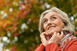 ritratto di anziano donna a piedi nel autunno parco foto