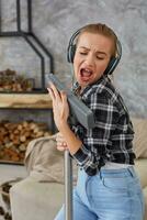 allegro giovane donna godendo assolo cantando con vuoto addetto alle pulizie mentre pulizia Casa foto