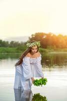 donna nel bianca vestito nel il acqua. arte donna con ghirlanda su sua testa nel fiume. ghirlanda su sua testa, slavo tradizioni e paganesimo foto