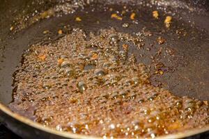 zucchero caramellare nel un' frittura padella a il gas stufa nel il cucina. vicino su foto