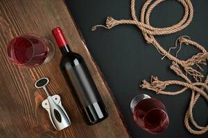 cavatappi, bottiglia di vino e Due bicchieri su il di legno tavola su nero sfondo. superiore Visualizza con copia spazio foto