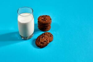 bicchiere di latte e biscotti su blu sfondo con spazio per testo o design foto