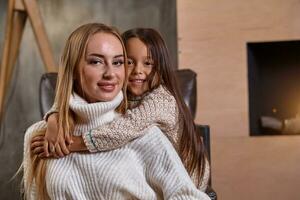 bellissimo madre donna nel bianca maglione abbracci sua poco figlia. allegro giocoso umore e amore dentro il famiglia. foto