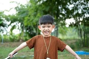 asiatico ragazzo in piedi con braccia diffusione nel un' rilassato posa a all'aperto la zona foto