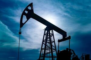 silhouette di un' pumpjack su un olio bene contro il sfondo di cielo foto