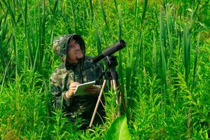 birdwatcher record il risultati di il osservazioni mentre in piedi tra il alto erba nel il zone umide foto