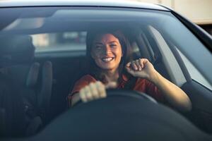 contento attività commerciale donna in viaggio con sua auto in giro il città. bellissimo giovane contento sorridente donna guida sua nuovo auto a tramonto. foto