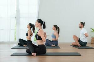 gruppo di persone praticante yoga nel un' studio. yoga classe concetto. foto