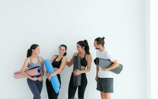 un' gruppo di femmina e maschio atleti si fermò e chiacchierato amichevolmente nel il studio prima inizio con il yoga classe. foto