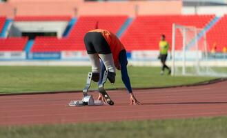 Disabilitato atleti preparare nel di partenza posizione pronto per correre su stadio traccia foto