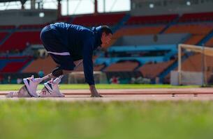 Disabilitato atleti preparare nel di partenza posizione pronto per correre su stadio traccia foto