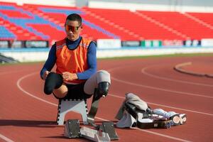 Disabilitato atleti preparare nel di partenza posizione pronto per correre su stadio traccia foto