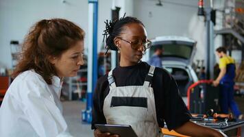 riparazione negozio lavoratori di brainstorming modi per fix macchina, utilizzando tavoletta e il computer portatile. colleghi manutenzione rotto veicolo, controllo per difettoso componenti utilizzando elettronico dispositivi, Ingrandisci su tiro foto