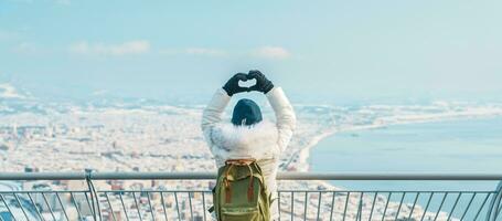 donna turista visitare nel hakodato, viaggiatore nel maglione giro turistico Visualizza a partire dal hakodate montagna con neve nel inverno. punto di riferimento e popolare per attrazioni nel hokkaido, giappone.travel e vacanza concetto foto