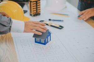 costruzione e struttura concetto di ingegnere o architetto incontro per progetto Lavorando con compagno e ingegneria utensili su modello edificio e planimetria nel Lavorando luogo, contrarre per tutti e due aziende. foto