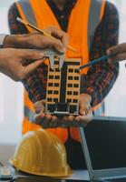 costruzione e struttura concetto di ingegnere o architetto incontro per progetto Lavorando con compagno e ingegneria utensili su modello edificio e planimetria nel Lavorando luogo, contrarre per tutti e due aziende. foto