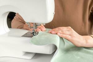 femmina mani Cucitura bianca tessuto su moderno cucire macchina a posto di lavoro nel Atelier foto
