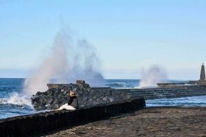 un' grande onda spruzzi in il acqua vicino un' molo foto