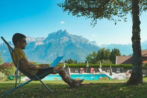 giovane uomo Lavorando con il computer portatile su bellissimo panoramico montagna sfondo. attraente uomo Lavorando. libero professionista. viaggiatore. foto