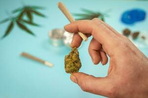 mano con CBD medico marijuana e canapa le foglie su turchese sfondo. foto
