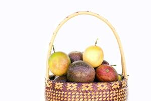 isolato passione frutta nel un' bambù cestino su bianca sfondo. il passione frutta ha un ovale forma, un' spesso, oleoso scorza. Là siamo molti semi dentro il frutta. esso è un' salutare frutta con alto fibra. foto