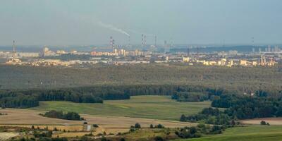 vista panoramica ariel della città e dei grattacieli con un'enorme fabbrica con camini fumanti sullo sfondo foto